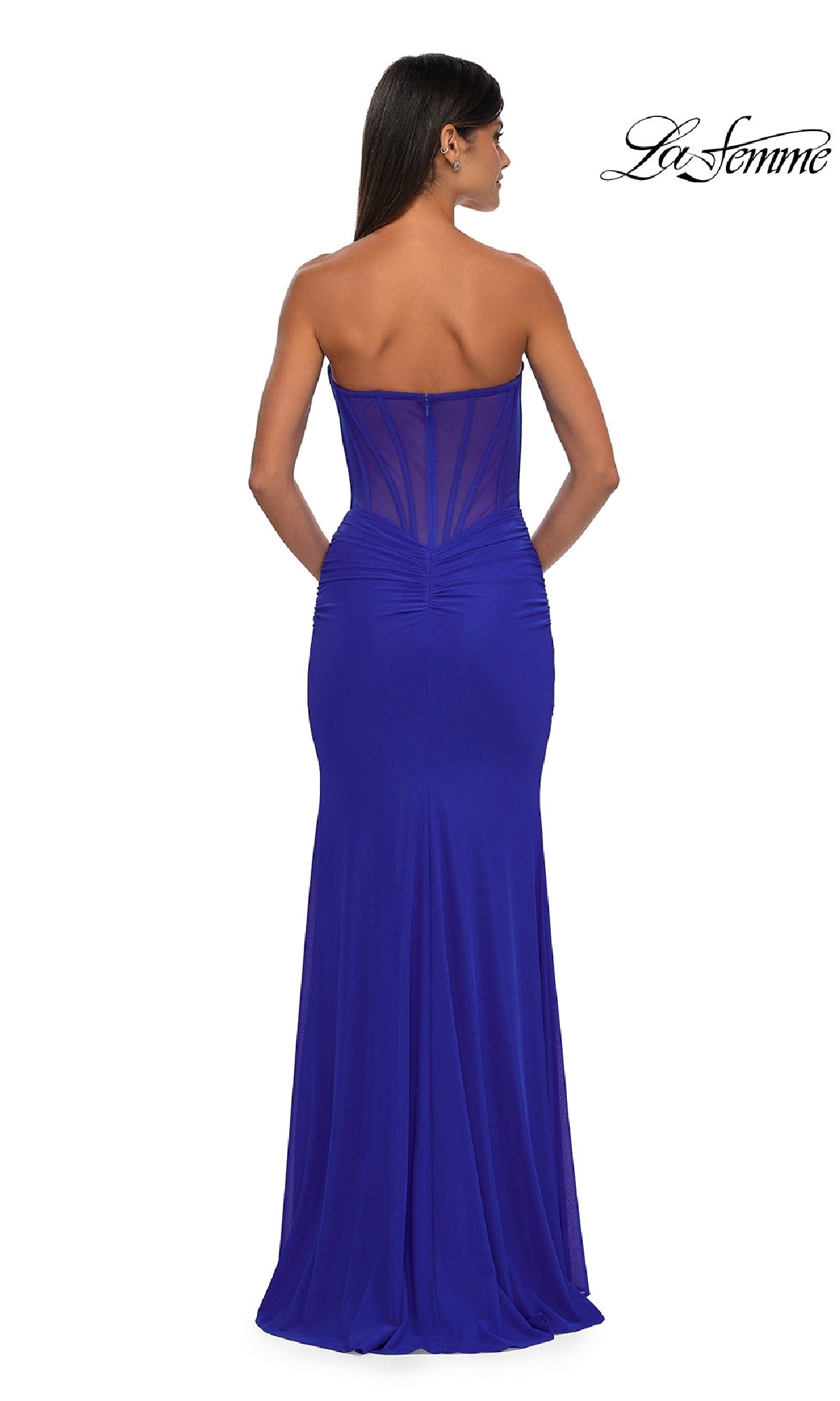 A woman models the La Femme 32734 Cut-Out Long Strapless Prom Dress in royal blue, featuring a sweetheart neckline, ruched details, a sheer back panel, and is posed facing away from the camera.